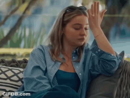 Woman In Blue Shirt Sitting On Couch Hand On Forehead GIF