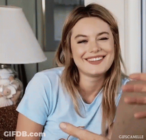 Woman In Blue Shirt Sitting On Couch Smiling GIF