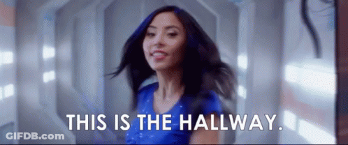 Woman In Blue Shirt Smiling In Hallway GIF