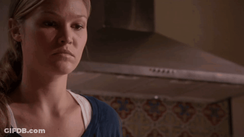 Woman In Blue Shirt Standing In Front Of Stove Hood GIF