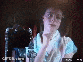 Woman In Blue Shirt With Hands Up In Dark Room GIF