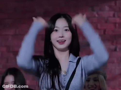 Woman In Blue Sweater Dancing In Front Of Brick Wall GIF