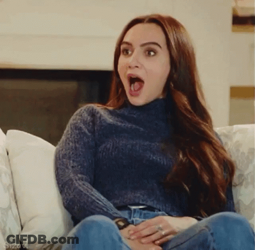 Woman In Blue Sweater With Mouth Open On Couch GIF