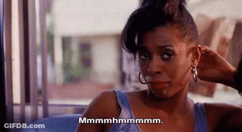 Woman In Blue Tank Top Sitting On Couch With Hair Bun GIF