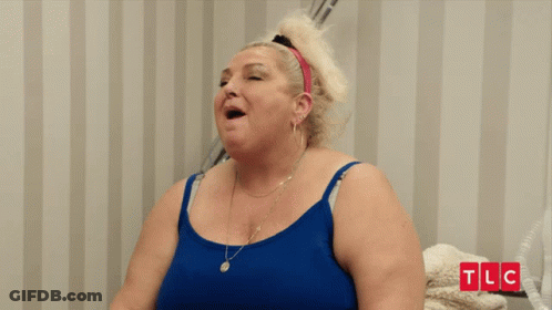 Woman In Blue Tank Top Smiling In Front Of TLC Wall GIF