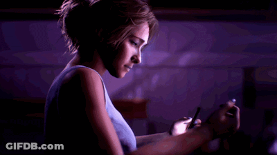Woman In Blue Tank Top Using Cell Phone In Dark Room GIF