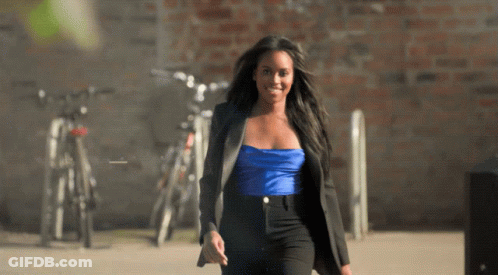 Woman In Blue Top And Black Pants Walking Down Sidewalk GIF