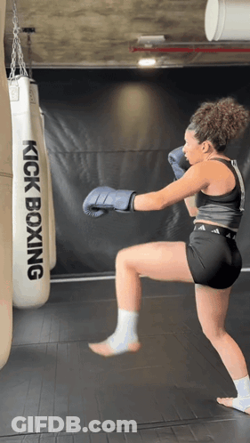 Woman In Boxing Gloves Kicking Kickboxing Bag GIF