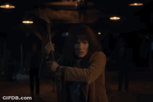 Woman In Brown Coat Holding Axe GIF