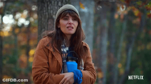 Woman In Brown Jacket Holding Blue Water Bottle In Forest GIF