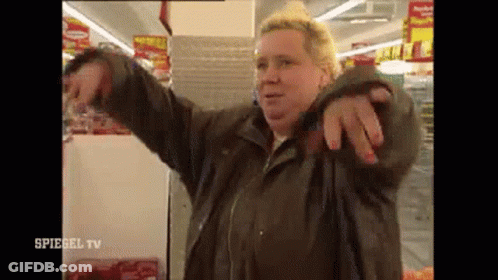 Woman In Brown Jacket Pointing At Camera GIF