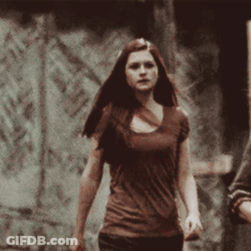 Woman In Brown Shirt In Front Of Stone Wall GIF