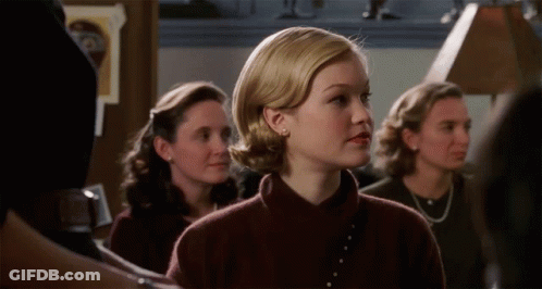 Woman In Brown Sweater Standing In Line With Others GIF