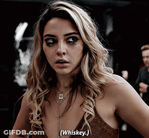 Woman In Brown Top Says Whiskey In Dark Room GIF