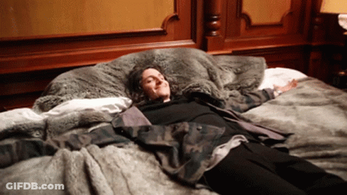 Woman In Camouflage Jacket Laying On Bed GIF