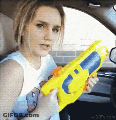 Woman In Car Holding Yellow Water Gun GIF
