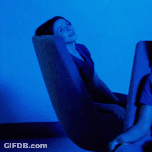 Woman In Chair With Blue Light In Dark Room GIF