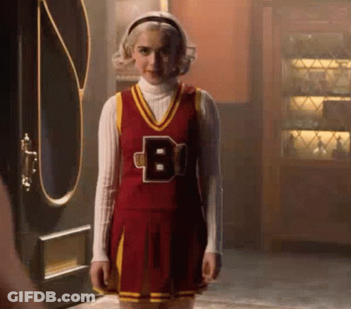 Woman In Cheerleader Costume Standing In Front Of Door GIF