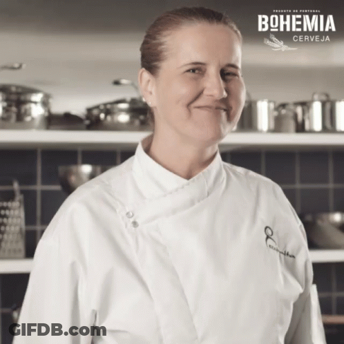 Woman In Chef's Coat Smiling In Front Of Bohemia Sign GIF