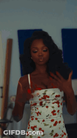 Woman In Cherry Print Dress In Front Of Blue Wall GIF