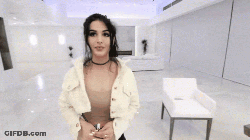 Woman In Choker And White Jacket Standing In Living Room GIF