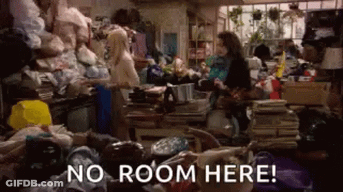 Woman In Cluttered Room With No Room Here Sign GIF