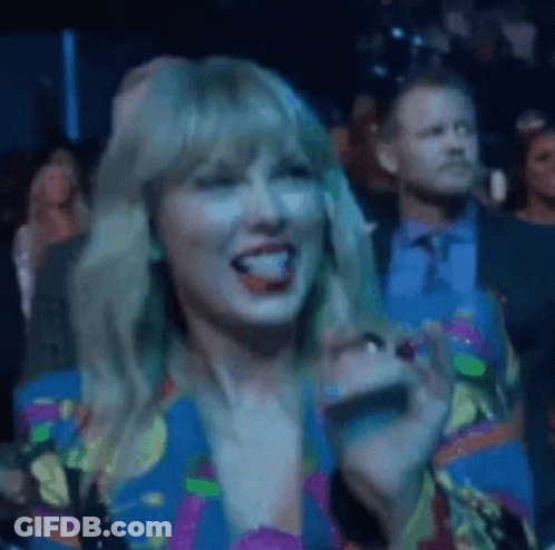 Woman In Colorful Dress Sitting In Crowd GIF
