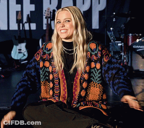 Woman In Colorful Sweater Sits In Front Of Therapy Banner GIF