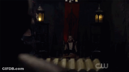 Woman In Costume In Dark Room With CW Logo GIF