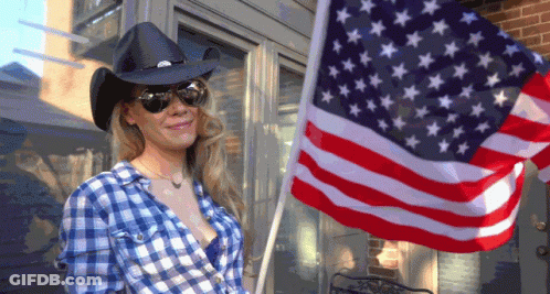 Woman In Cowboy Hat And Plaid Shirt Holding American Flag GIF