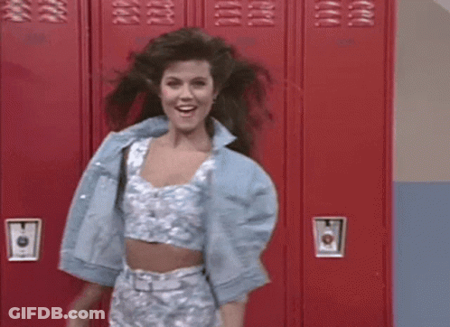 Woman In Crop Top And Denim Jacket In Front Of Red Lockers GIF