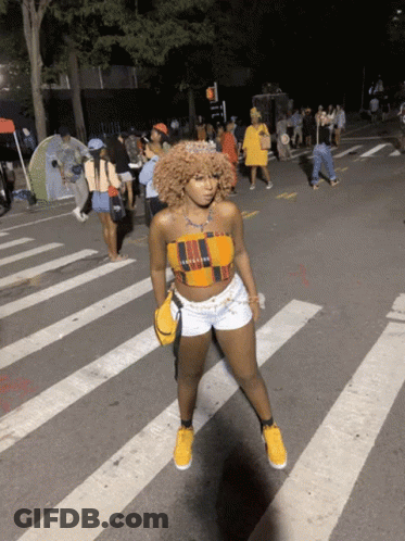 Woman In Crop Top And Shorts Crossing Street At Night GIF