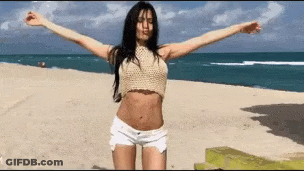Woman In Crop Top And Shorts With Arms Outstretched On Beach GIF