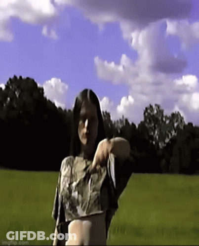 Woman In Crop Top Standing In Grassy Field GIF