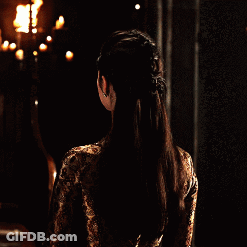 Woman In Dark Room Candles Looks At Camera GIF