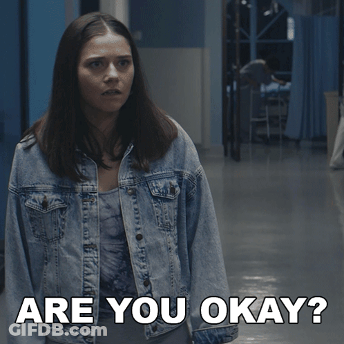 Woman In Denim Jacket Asking Are You Okay In Hallway GIF