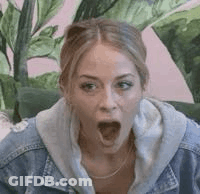 Woman In Denim Jacket Sitting On Couch With Mouth Open GIF