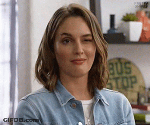Woman In Denim Jacket Smiling And Winking GIF