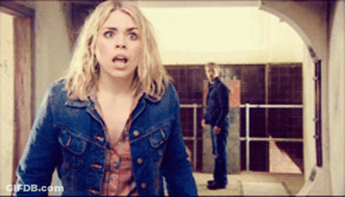 Woman In Denim Jacket With Man Behind Her In Hallway GIF