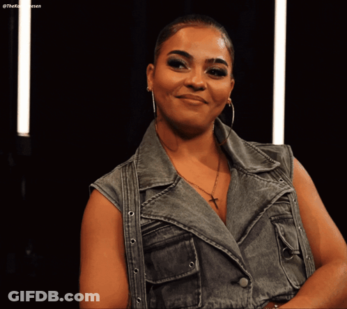 Woman In Denim Vest And Hoop Earrings Smiling GIF