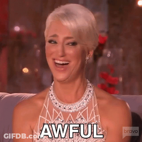 Woman In Dress And Necklace Smiling On Couch GIF