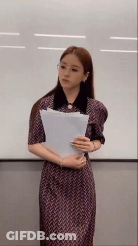 Woman In Dress Holding Paper In Front Of White Board GIF