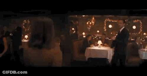 Woman In Dress Looking Over Shoulder In Restaurant GIF