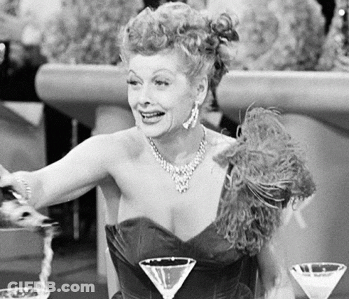 Woman In Dress Sitting At Table With Two Martinis GIF