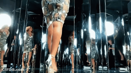 Woman In Dress Walking Through Room Of Mirrors GIF