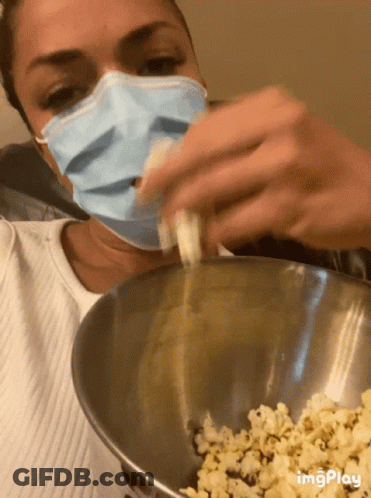 Woman In Face Mask Pouring Popcorn Into Bowl GIF