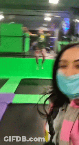 Woman In Face Mask Standing In Front Of Trampoline GIF