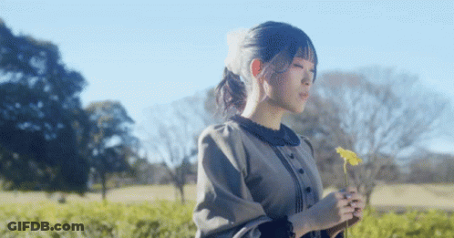 Woman In Field Holding Yellow Flower GIF