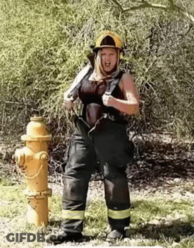 Woman In Firefighter Costume Next To Fire Hydrant GIF