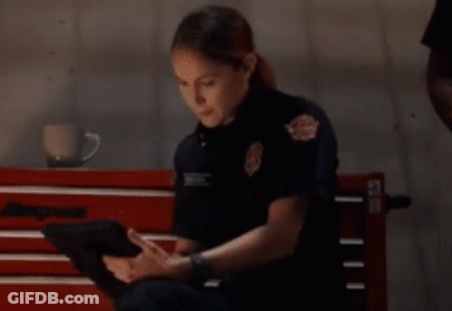 Woman In Firefighter Uniform Sitting On Bench Using Tablet GIF